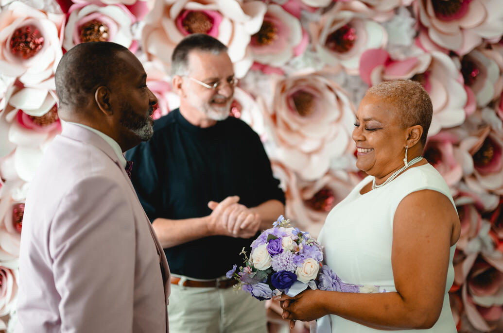 Peter Marries a Couple in Our office Marry Me In Indy flower wall.